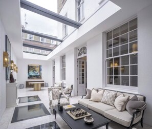 A spacious living area with a high ceiling, a sofa set, a chessboard, and a large window. - Luxury city retreat in Mayfair w/pool. Pet-Friendly! (London)