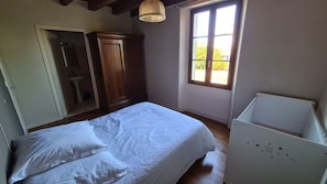 A bedroom with a bed, a wardrobe, a window, and a crib. - New Listing (Saint-Saturnin-du-Bois)
