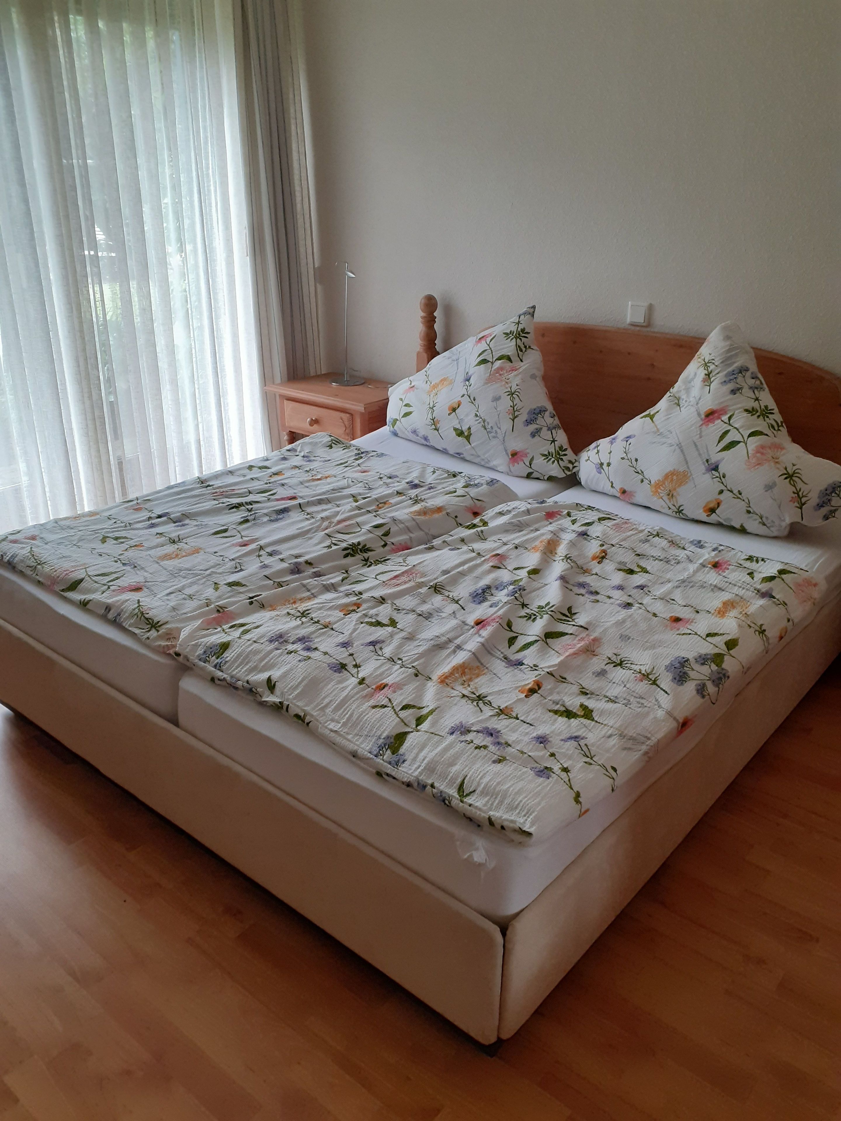 Een slaapkamer met een bed, houten hoofdeinde en een nachtkastje met een lamp.