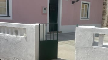 Ein rosafarbenes Gebäude mit einer grünen Tür, einem weißen Geländer und einem kleinen Podest zum Eingang.