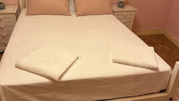 A bed with a white headboard, two pillows, and a folded towel on the bed.