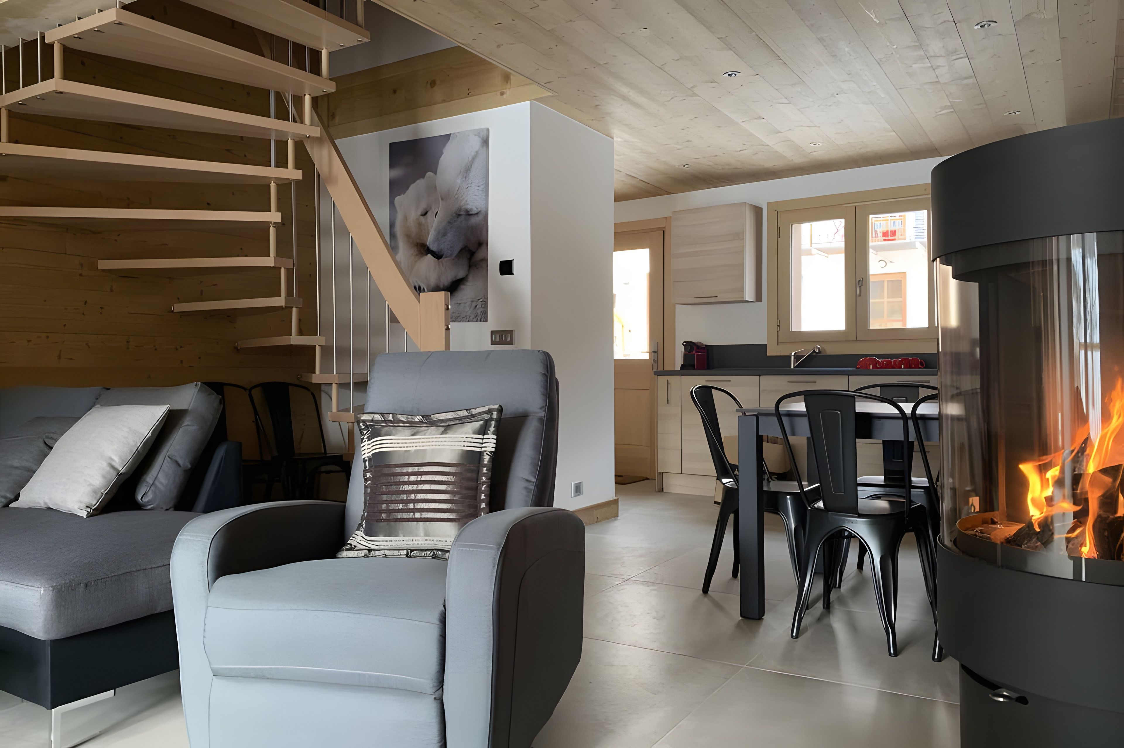 A modern living room with a grey sofa, a black chair, and a fireplace.
