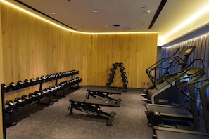 Un gimnasio con cintas de correr, bancos de pesas y mancuernas.