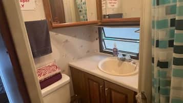 A compact bathroom with a toilet, sink, and mirror.
