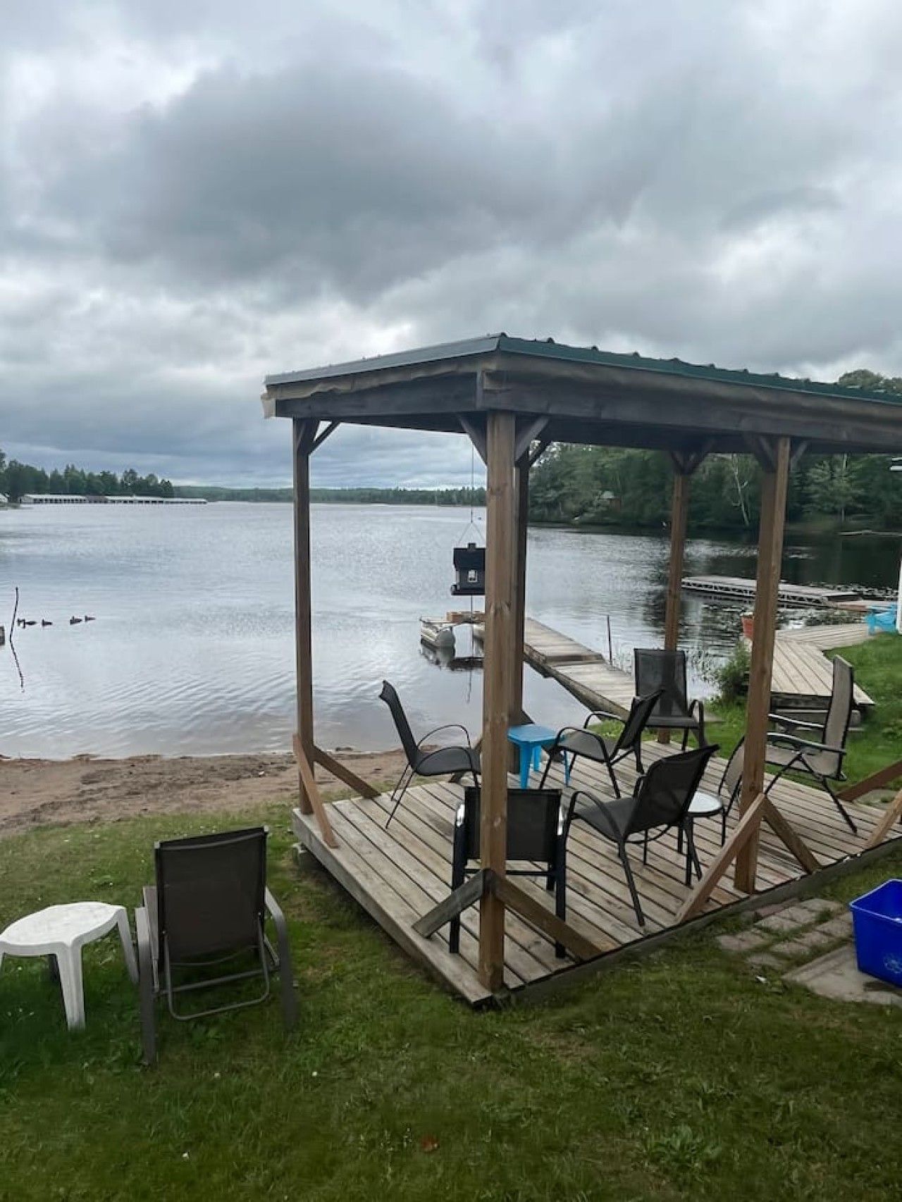 A covered outdoor seating area with chairs and tables, overlooking a body of water.