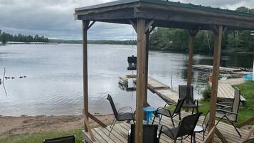 A covered outdoor seating area with chairs and tables, overlooking a body of water.