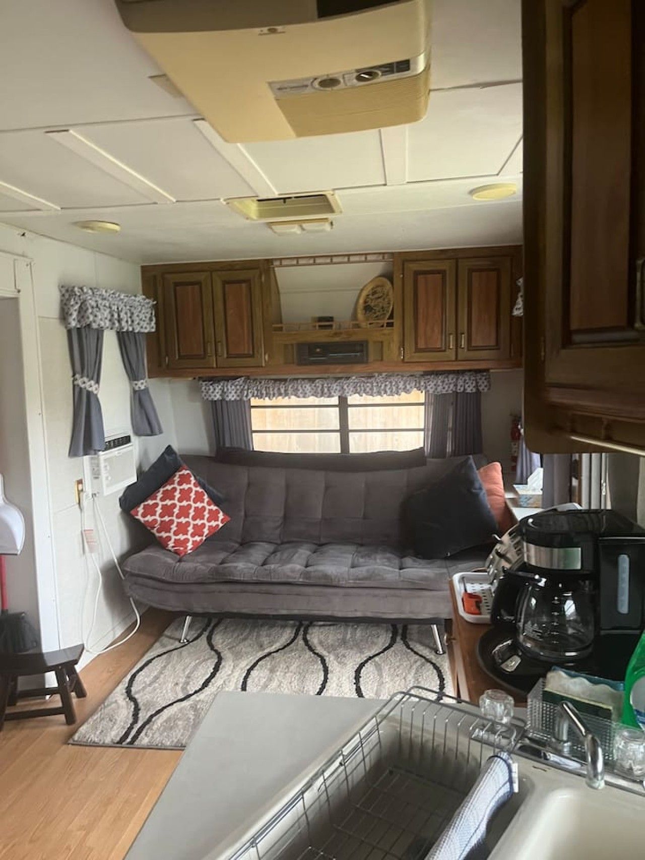 A compact RV interior with a kitchenette, a sofa, and a dining area.