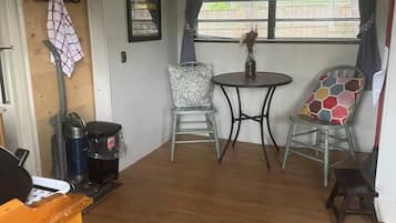 A compact living space with a dining table, two chairs, a coffee machine, and a small rug.