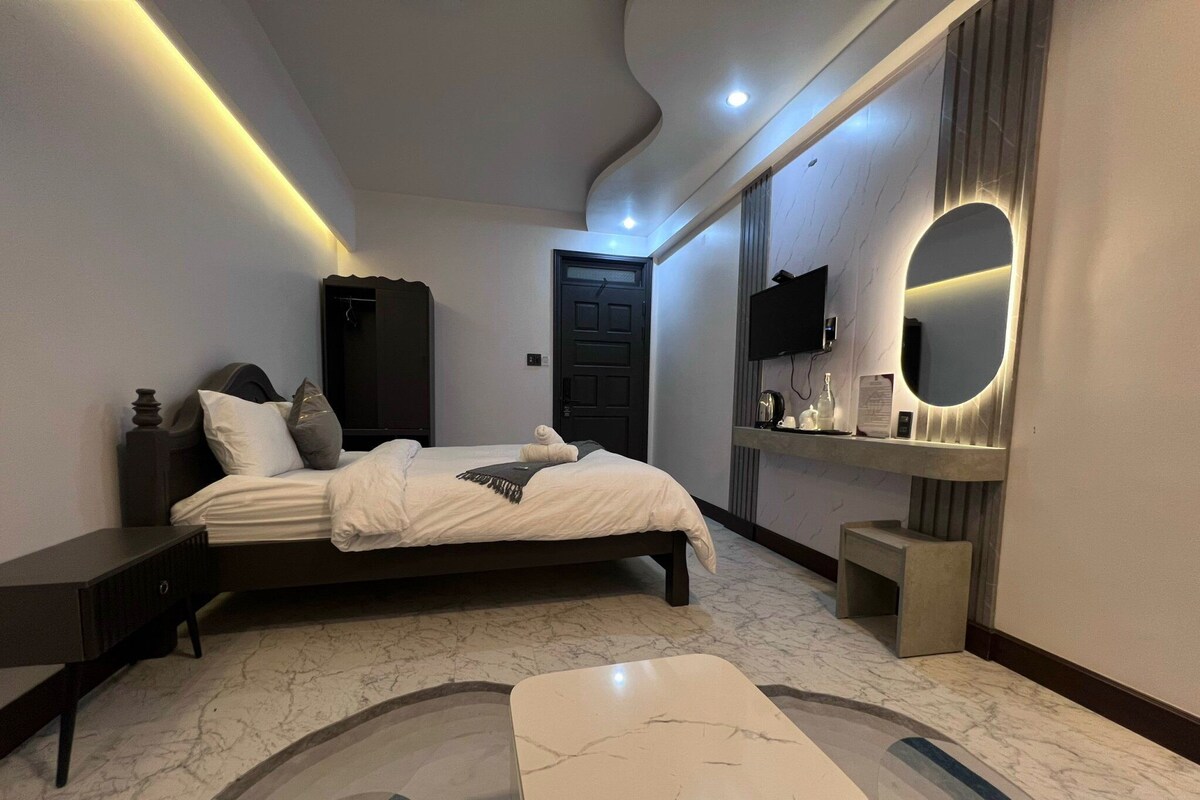 A modern bedroom with a bed, bedside tables, a mirror, and a marble floor.