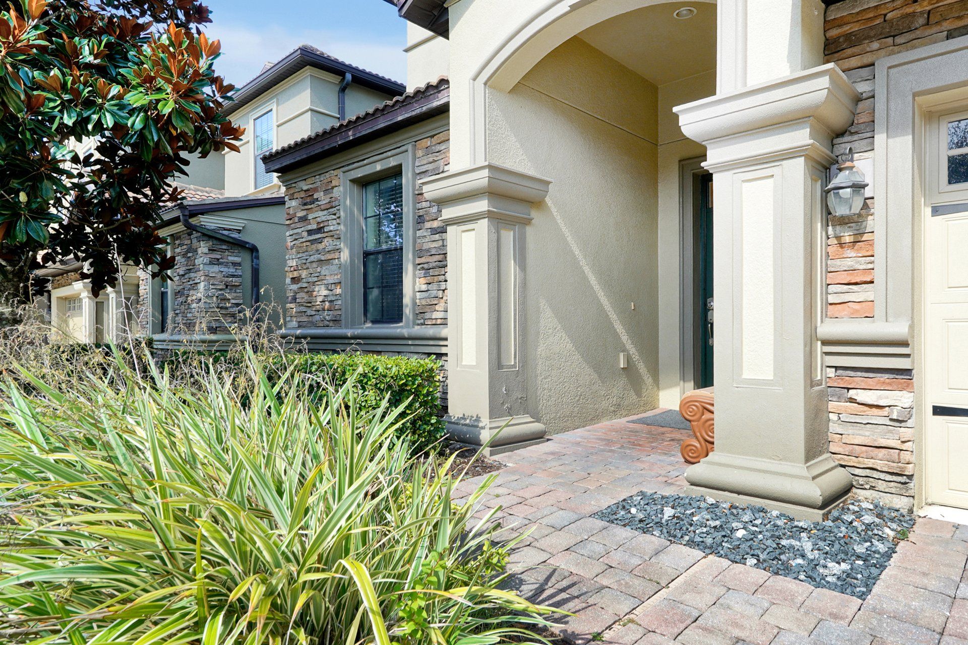 A residential building with a stone facade, a brick pathway, and a well-maintained garden.