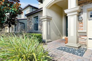 A residential building with a stone facade, a brick pathway, and a well-maintained garden. - Just a Dream Away: 9-Bedroom Pool and Spa Home with Game Room (ChampionsGate)
