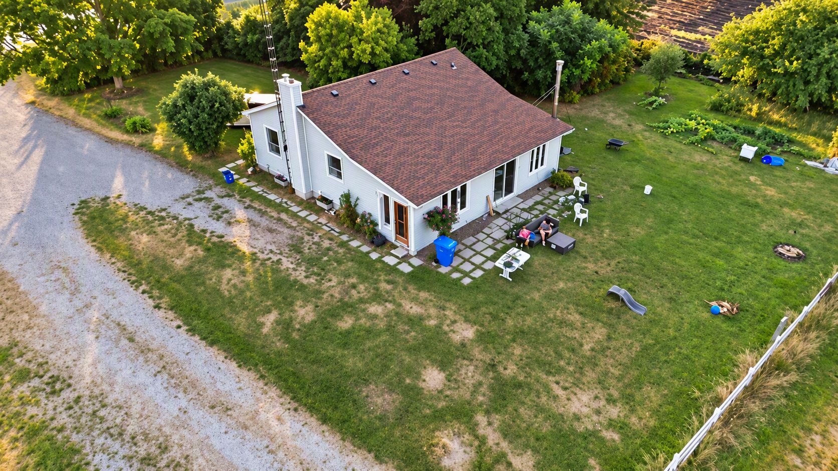 Une maison à deux étages avec un toit recouvert de tuiles rouges, une véranda à l’avant avec des sièges d’extérieur et une pelouse bien entretenue.