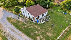 A two-story house with a red-tiled roof, a front porch with outdoor seating, and a well-maintained lawn.