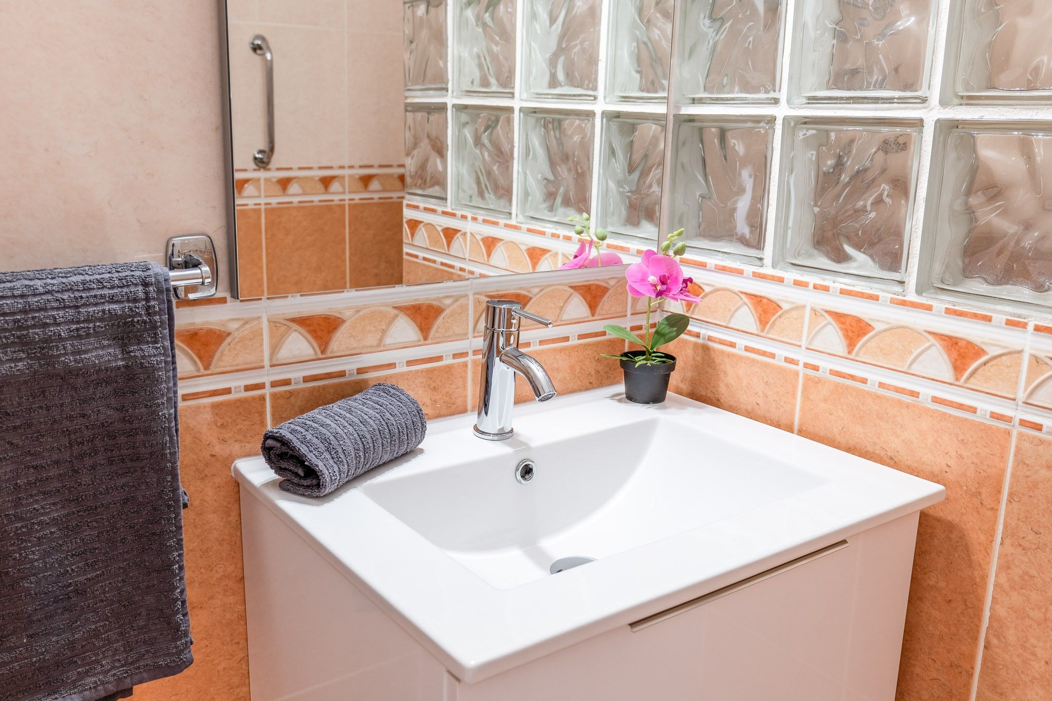 A bathroom with a white sink, a towel, a potted plant, and a window with a view.