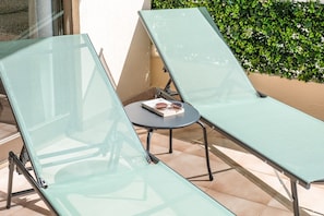 Twee fauteuils met een bijzettafeltje ertussen, een boek en een zonnebril op het tafeltje.
