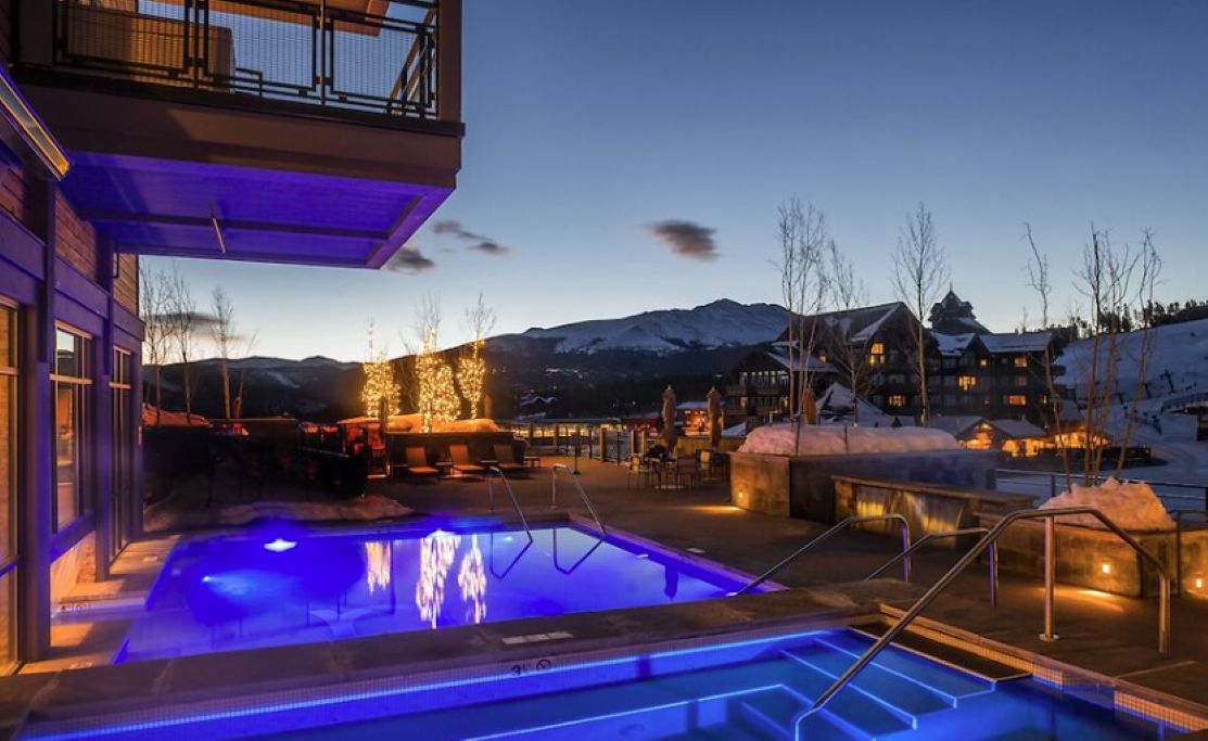 A pool area with a view of snow-covered mountains at dusk.