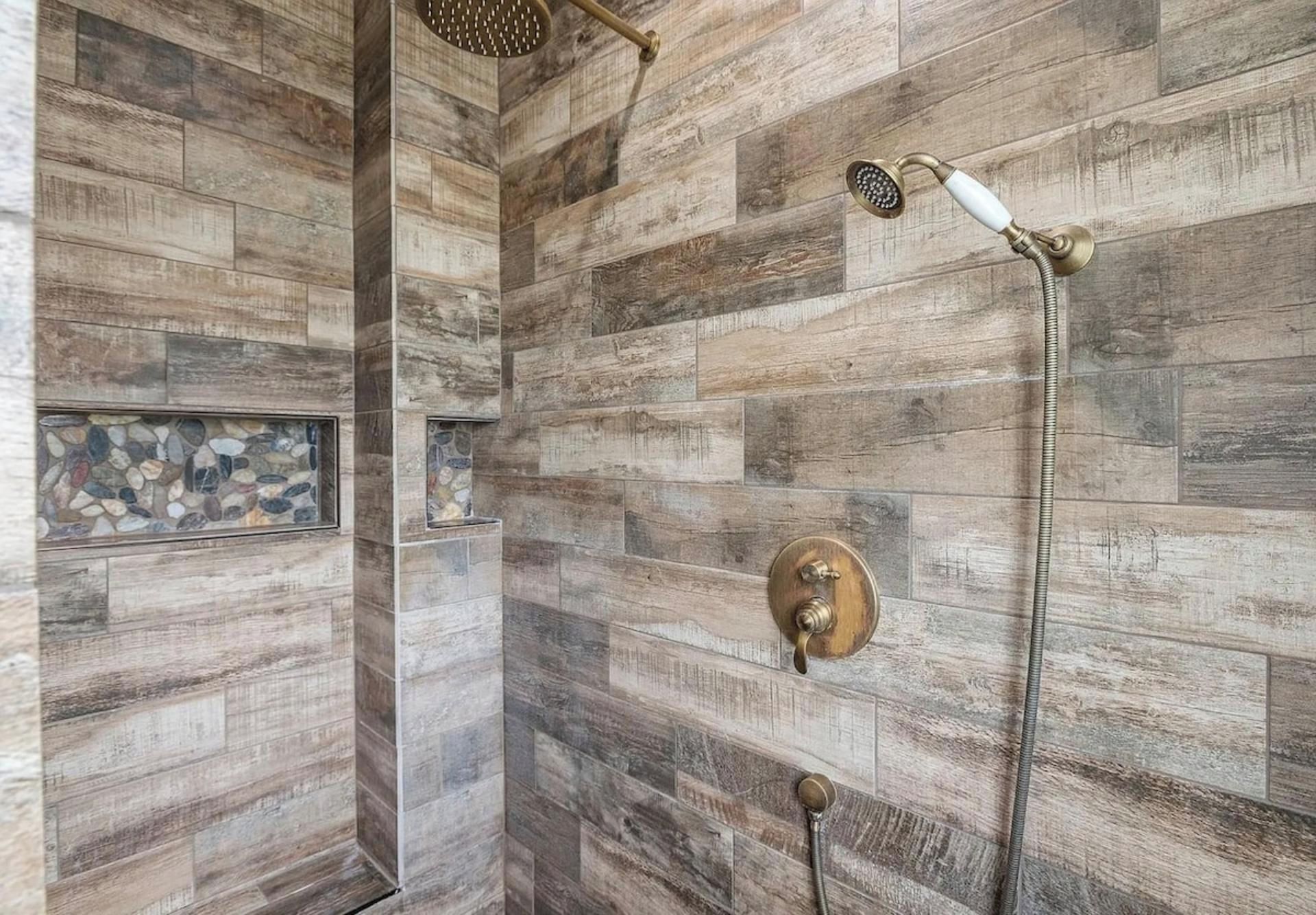 A shower with a wooden wall design, a handheld showerhead, and a wall-mounted control valve.