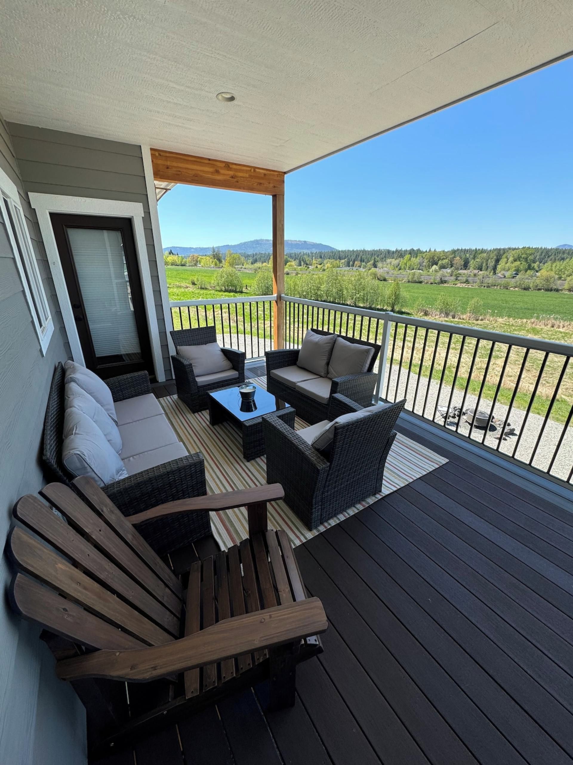 Un balcon avec des meubles d’extérieur, une porte et une vue sur un paysage verdoyant.