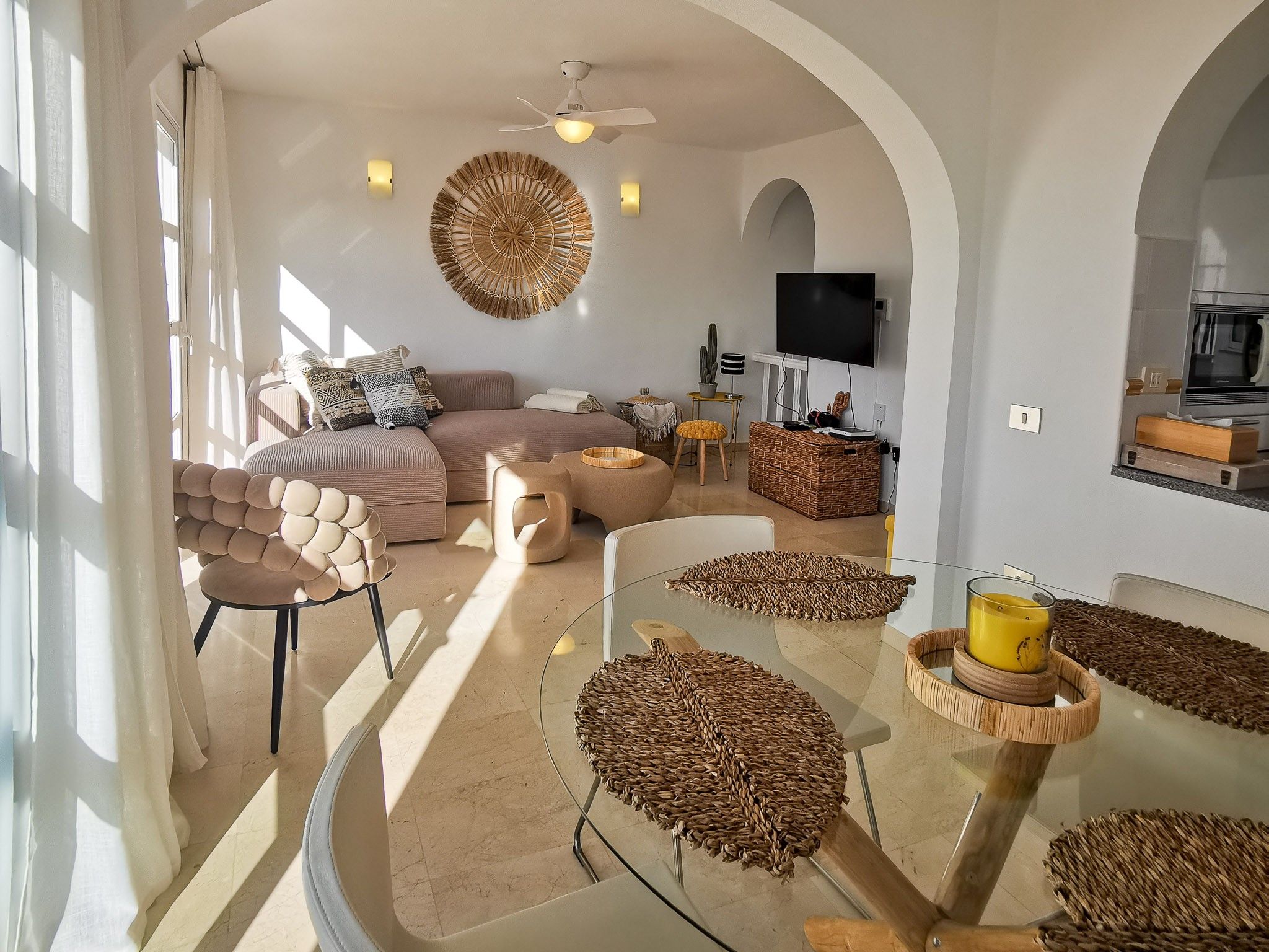 Una sala moderna con un sofá modular, una mesa de centro de vidrio y un televisor montado en la pared.