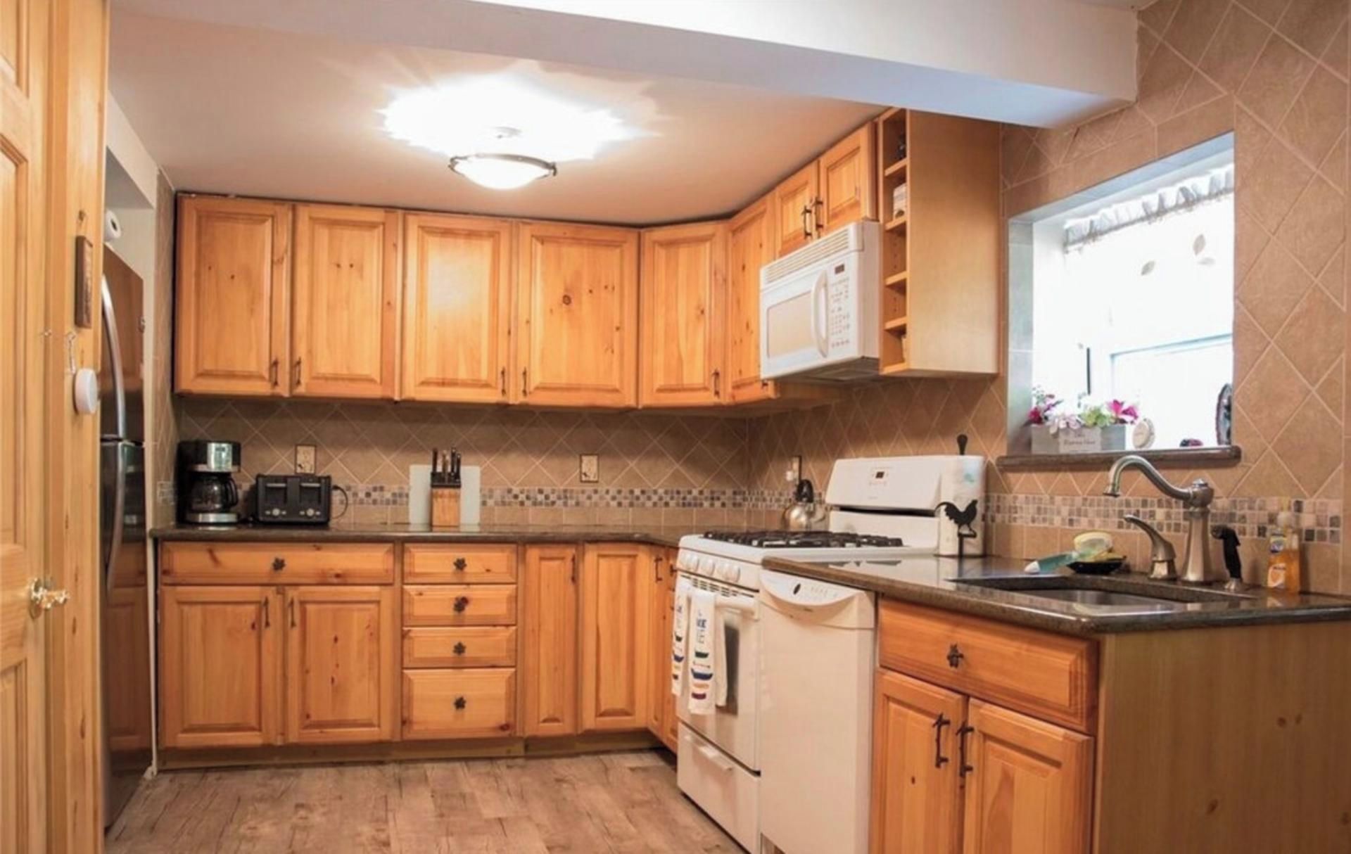 A kitchen with wooden cabinets, a stove, a microwave, and a sink.