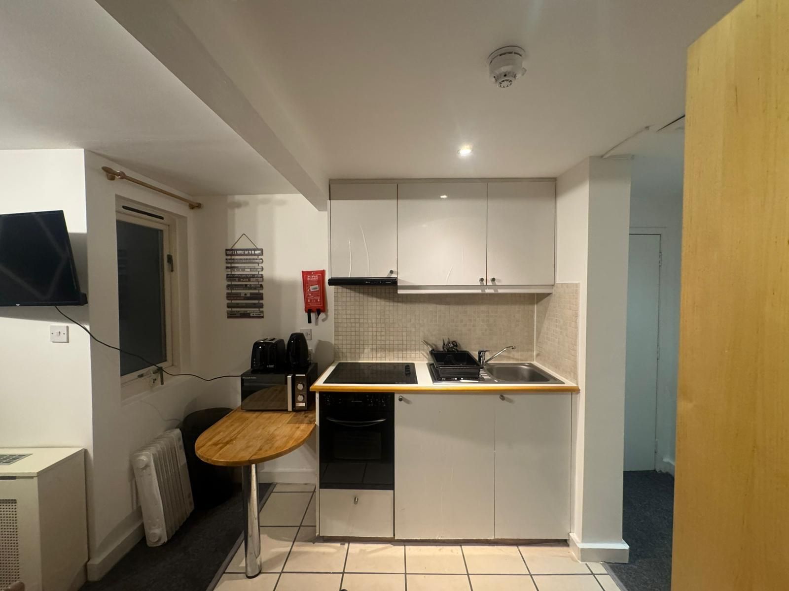 A compact kitchen with white cabinets, a small countertop, a stove, and a sink.