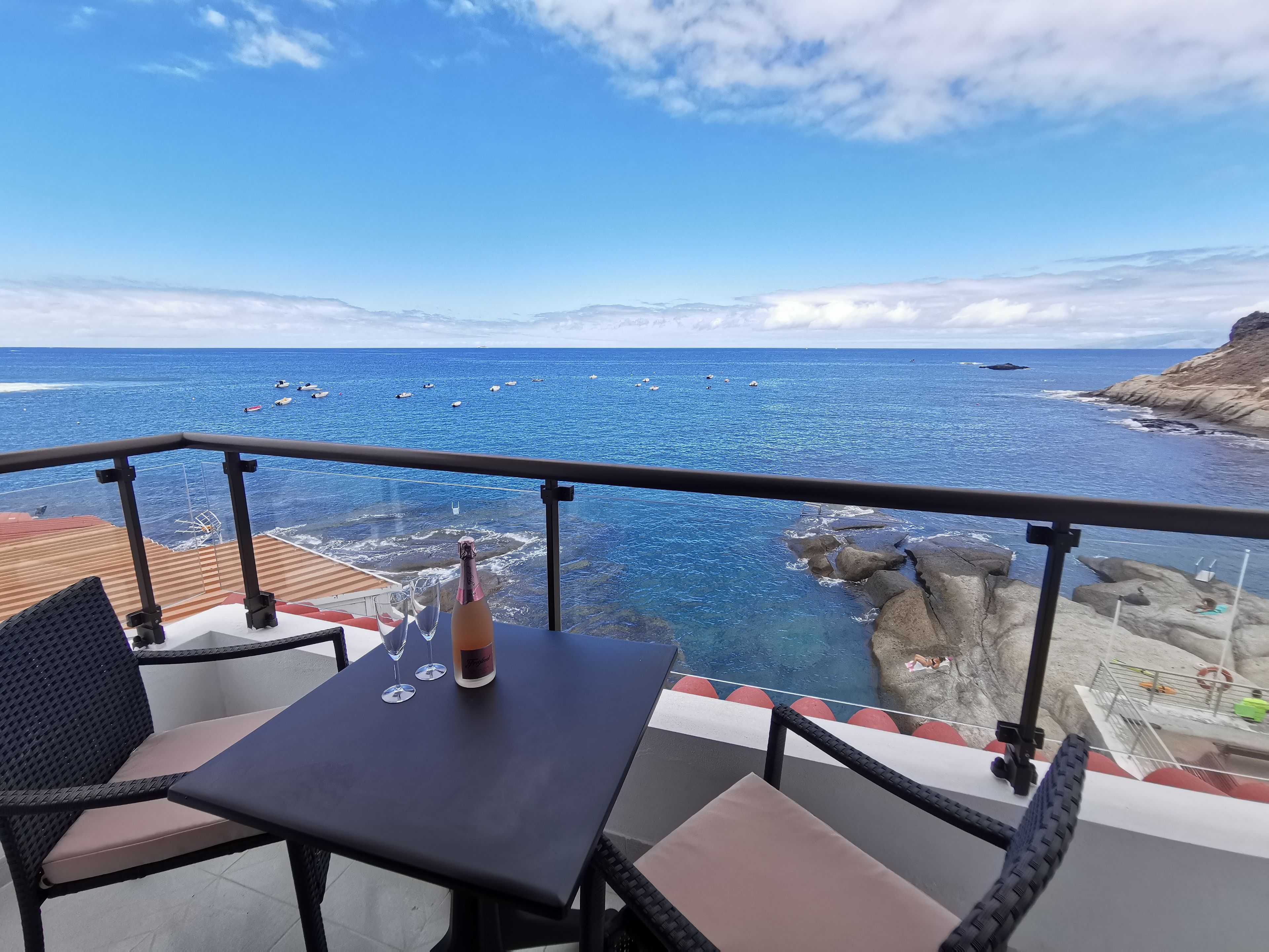 A balcony with a table, chairs, and a bottle of champagne.