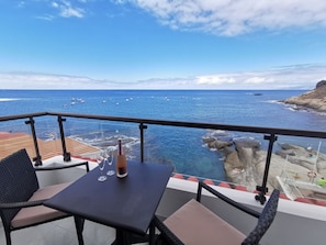 Een balkon met een tafel, stoelen en een fles champagne.