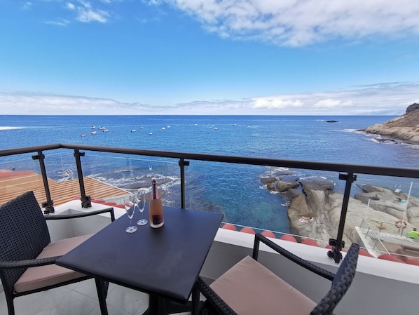 A balcony with a table, chairs, and a bottle of champagne.