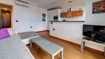 Een modern appartement met een woonkamer, kitchenette en een televisie.