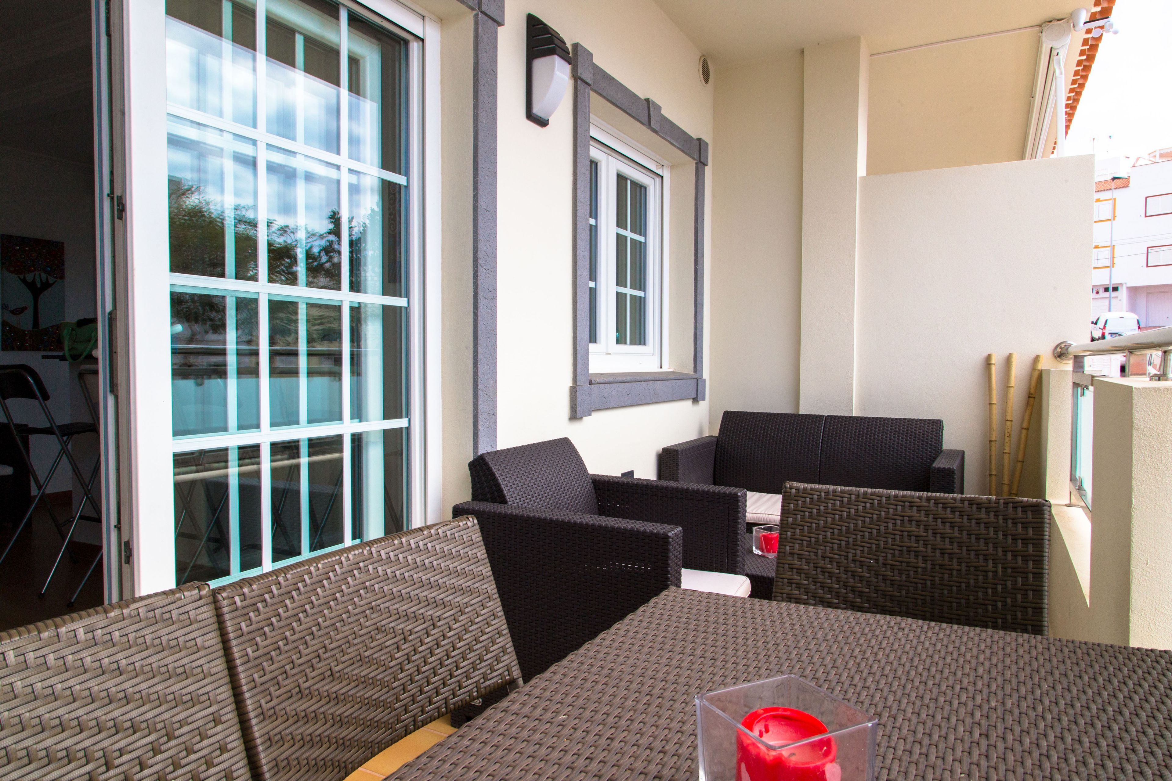 Een terras met rieten meubilair, een glazen deur en een raam.