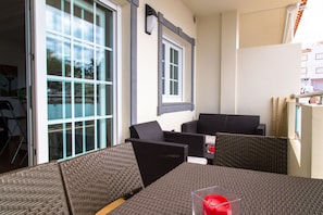 Een terras met rieten meubilair, een glazen deur en een raam.