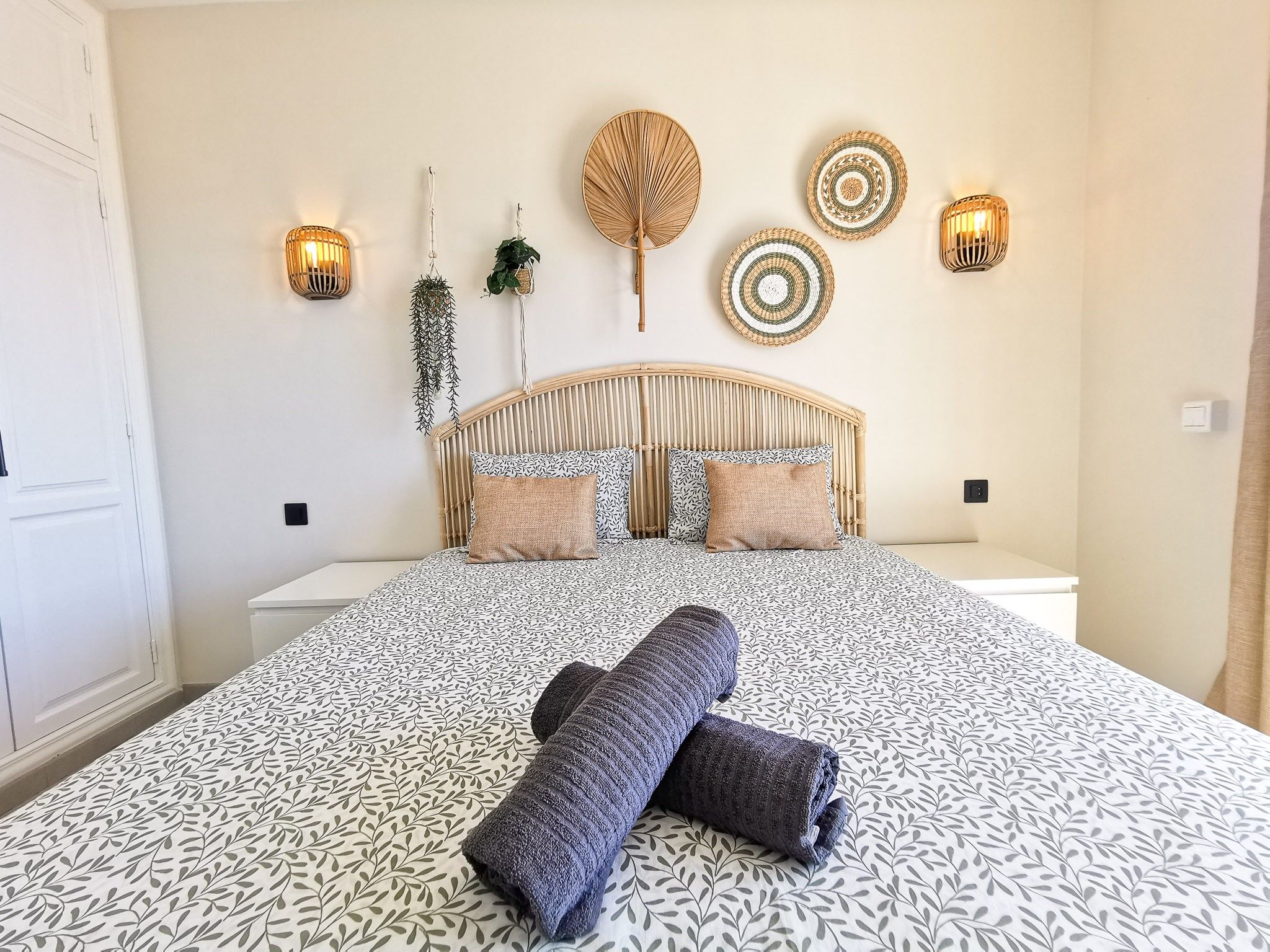 Een bed met een beddegoed met dessin, een hoofdbord en decoratieve wandkunst.