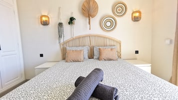 Een bed met een beddegoed met dessin, een hoofdbord en decoratieve wandkunst.