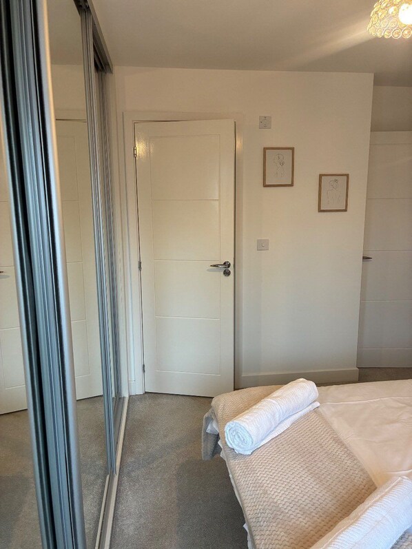 Une chambre d’hôtel avec un lit, une porte et un mur orné de deux tableaux encadrés.