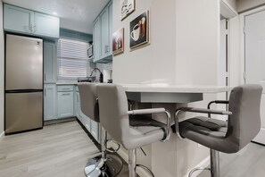 Eine moderne Küche mit einem Edelstahl-Kühlschrank, einem Einbauofen und einem Fenster mit Jalousien.