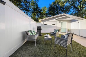 Un pati d'habitatge amb zona de terrassa, mobles d'exterior i una barbacoa.