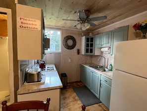 Une cuisine de taille réduite, équipée d’un évier, d’une cuisinière et d’un ventilateur de plafond.