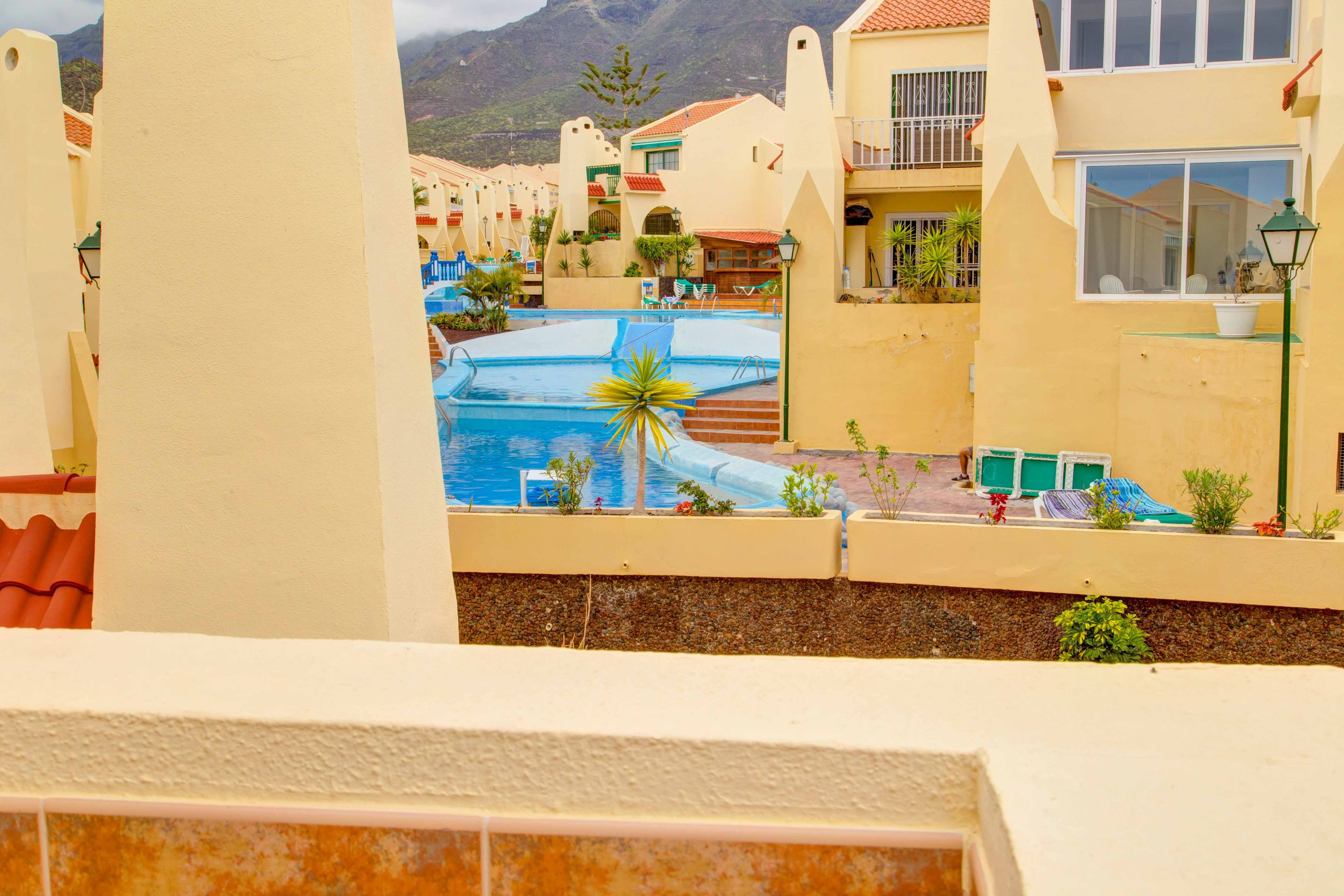 Een resort met een zwembad, meerdere balkons en een bergachtig decor.