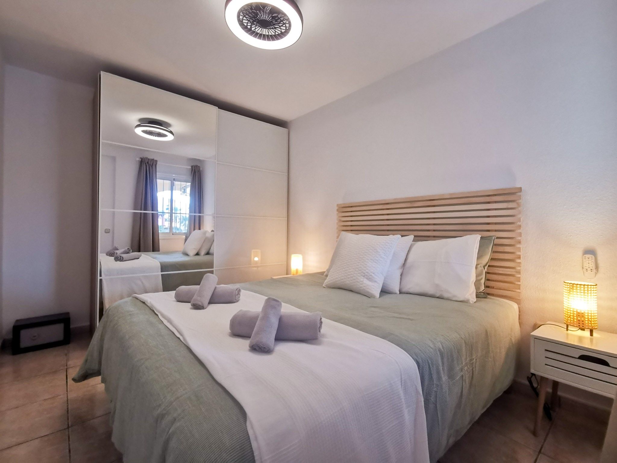 Et moderne hotelværelse med en stor seng, et sengebord med lampe, et spejl og udsigt ud