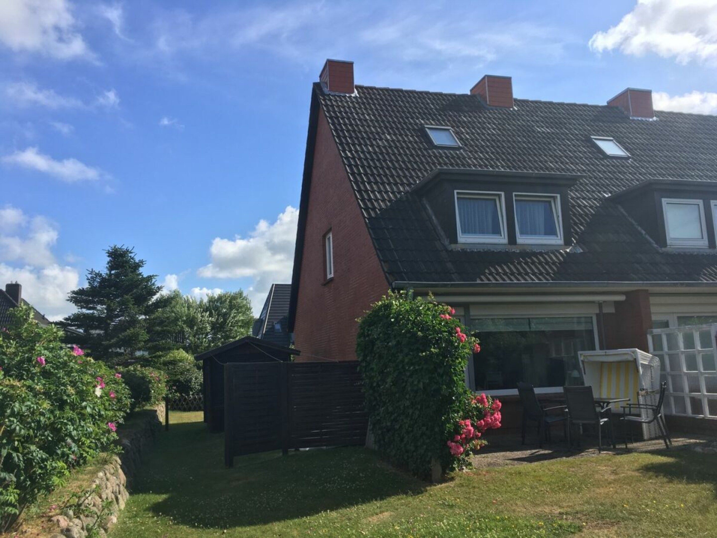Une maison d’habitation avec un toit en pente, une cour arrière clôturée et un garage visible.