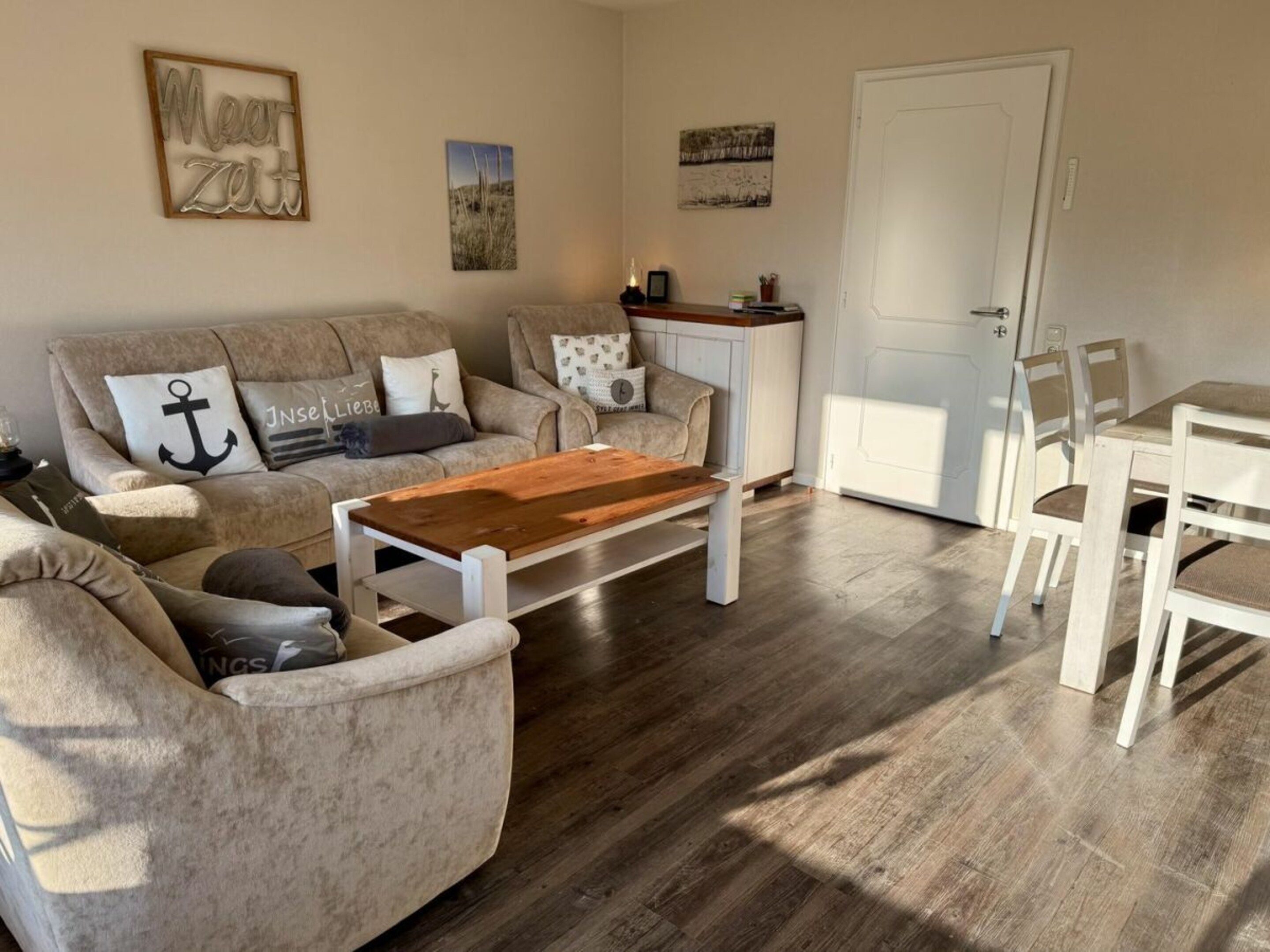 Een woonkamer met een bank, salontafel en een eethoek met stoelen.