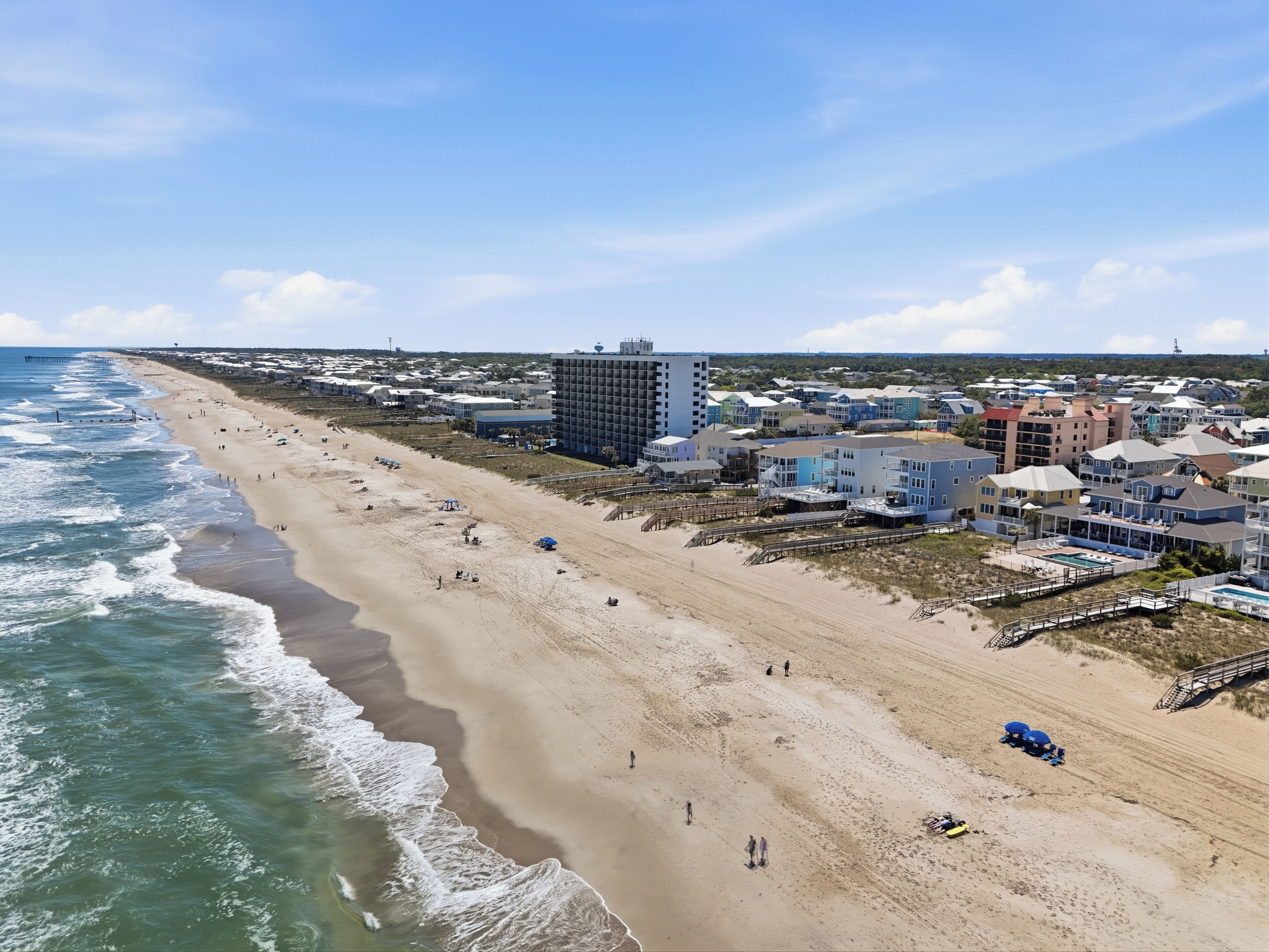 Une zone côtière comprenant une plage, des bâtiments et une jetée.