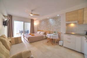 Een hotelkamer met een bed, een bank, een eettafel en een kitchenette.