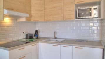 A modern kitchen with white cabinets, a stainless steel microwave, and a built-in oven.