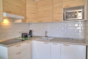 Een moderne keuken met witte kasten, een roestvrijstalen magnetron en een inbouwoven.
