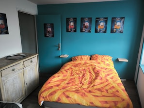 A bedroom with a bed, a dresser, and wall art.