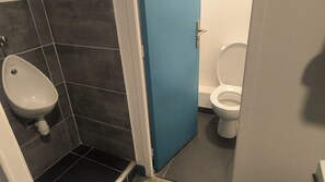 Une salle de bain avec un urinoir, des toilettes et une porte bleue.