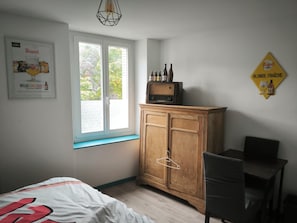 Une chambre à coucher avec un lit, une armoire en bois, une chaise, une fenêtre et une radio fixée au mur.