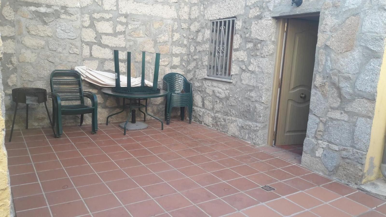 Une terrasse aux murs de pierre, dotée d’un sol carrelé, d’une table avec des chaises et d’une porte.