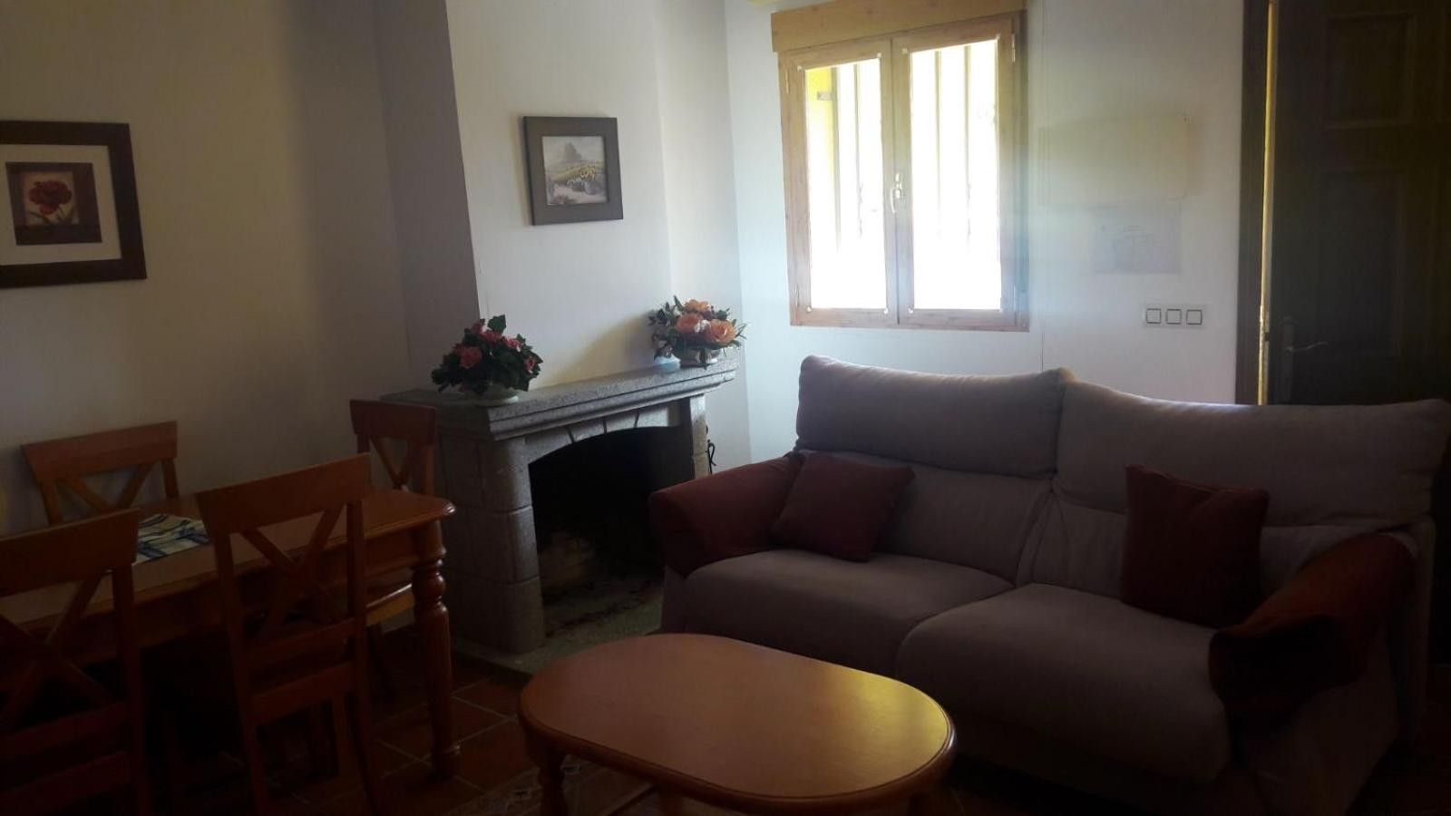 Un salon comprenant un canapé, une cheminée, une table à manger avec des chaises et une fenêtre.